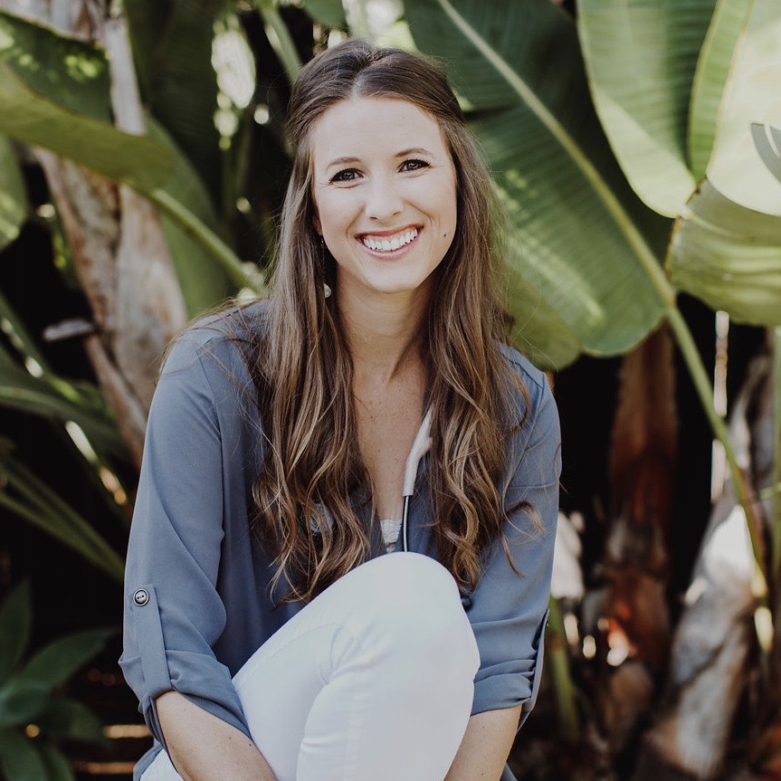 Dr. Leah Gordon smiling at the camera in front of lush greenery